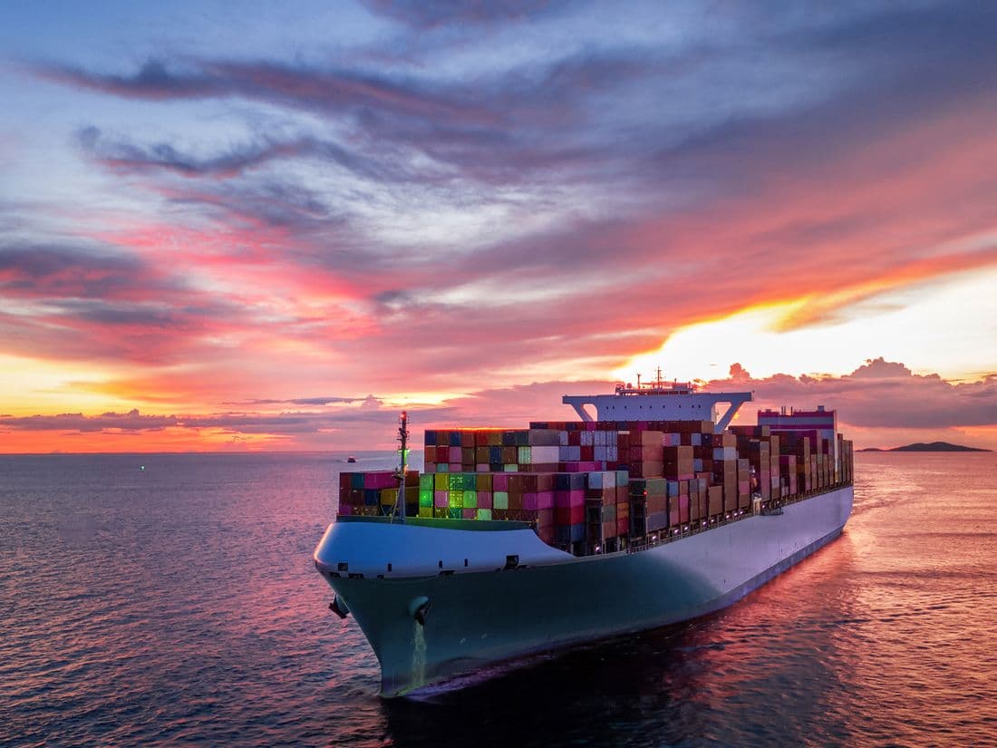 Navio porta-contêineres em operação portuária ao pôr do sol